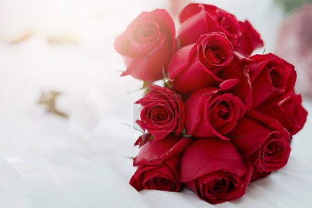 Photo for Home, bedroom and bunch of red roses, sunshine and lens flare with flora, summer and decoration. Empty, love and bed with flowers, sunlight and nature with gift, present for Valentines day or bouquet. - Royalty Free Image