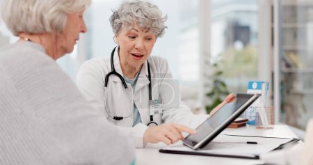 Photo for Senior doctor, tablet and discussion with patient for healthcare prescription or diagnosis at hospital. Mature medical professional talking to elderly female person on technology for consultation. - Royalty Free Image