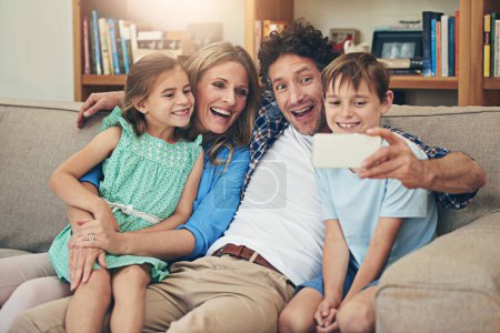 Photo for Family, selfie and parents with children, couch and laughing for joke by dad, funny face and comedy in house. Home, woman and man with kids, together and bonding with photography for memory in phone. - Royalty Free Image