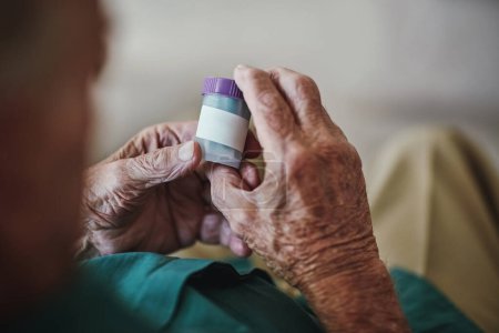 Foto de Senior person, hands and reading with pills for illness, medication or sickness symptoms at old age home. Closeup of elderly or chronic patient checking container for medical dose or side effects. - Imagen libre de derechos