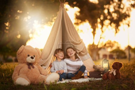 Téléchargez les photos : Teepee, kids and fun in garden tent outdoor in nature for camping, playing and adventure with sunlight. Cloth, happy and fantasy house for children in forest with imagination, suitcase and teddy bear. - en image libre de droit