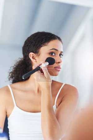 Téléchargez les photos : Makeup brush, mirror and black woman with beauty in bathroom for cosmetics, makeover or foundation. Lens Flare, hand and person with tools for contour powder, glowing skin or morning routine in home. - en image libre de droit