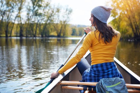 Téléchargez les photos : Woman, back and canoeing in forest on water, wellness hobby and backpack for supplies with paddle for rowing. Vacation, relax and explore exercise on travel holiday, canoe boat and trees on river. - en image libre de droit