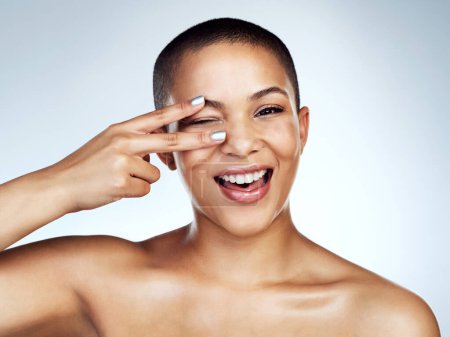 Beauty, peace sign of eye and portrait with black woman in studio on blue background for wellness. Aesthetic, cosmetics and smile of happy model with clear skin for natural dermatology or vitamin c.