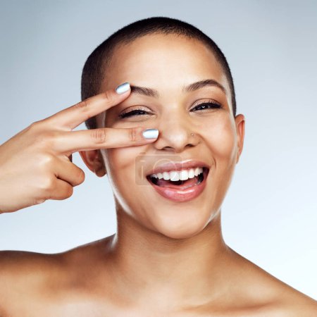Peace sign on eye, portrait and skincare with black woman in studio on blue background for natural aesthetic. Beauty, cosmetics or smile and face of happy model satisfied with vitamin c dermatology.