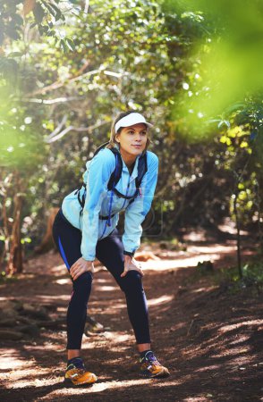 Photo for Tired, runner and woman hiking in nature on trail or outdoor adventure to explore on holiday vacation. Girl, rest break or hiker trekking in woods for running training, fitness or travel with fatigue. - Royalty Free Image