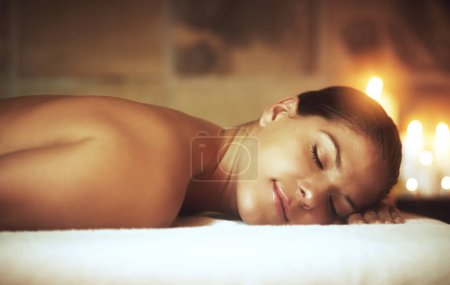 Téléchargez les photos : Femme, détendez-vous et zen dans le spa sur lit de massage pour la lueur, le bien-être et les cosmétiques avec des bougies. Traitement, beauté et sommeil en paix après aromathérapie, tissus profonds et soulagement du stress avec de l'huile pour le luxe. - en image libre de droit