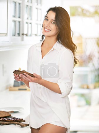 Happy, woman and buttering toast for breakfast in kitchen for healthy food, morning routine and nutrition. Smile, female person and cooking bread for organic start to day at home for wellness.