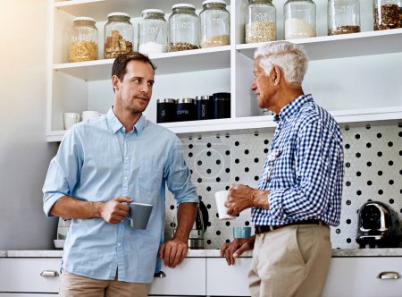 Man, advice and senior father in kitchen with conversation in morning with coffee for help or consult in retirement. Proud, dad and son on weekend together in home for family dinner in Switzerland