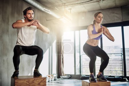 Jump, fitness and couple in training with box, power and gym for workout challenge together. Man, woman and personal trainer with balance, muscle development and healthy body exercise at sports club.