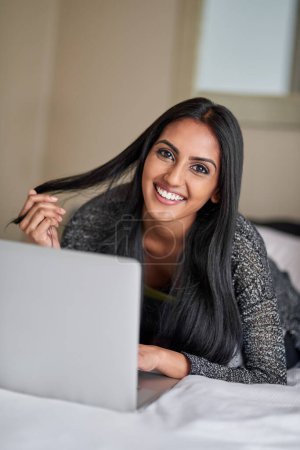 Photo for Laptop, typing and Indian woman in bed for online, social media and portrait with internet in bedroom. Email, technology and computer for blog or freelance writer person, creative and work from home. - Royalty Free Image