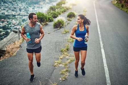 Photo for Fitness, running and couple with smile, routine and bottle for hydration with water and outdoor. Road, exercise and people in morning, sportswear and training together, energy and workout for race. - Royalty Free Image