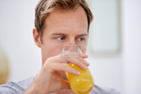 Man, morning and drinking orange juice in home for vitamin c health or citrus beverage, breakfast or antioxidants. Male person, glass and wellness micronutrients in apartment, immune system or relax.