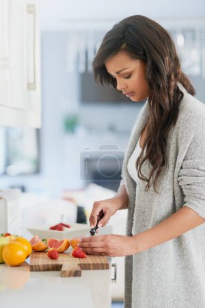 Fruta, ensalada y mujer en la cocina para el desayuno con los beneficios de la vitamina C, la nutrición y la dieta. Saludable, comida y chica rebanada de fresa orgánica y naranja en la mesa en casa con cuchillo para merienda vegana.