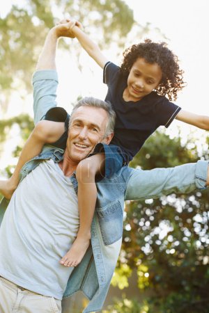 Photo for Garden, portrait and child fly dad in backyard with freedom, happiness and support. Kid, games or fathers day with interracial family outdoor in park on holiday or vacation and carry boy on shoulders. - Royalty Free Image