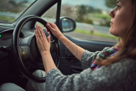 Woman, car and driving with honk on road for alert, emergency or traffic in travel, trip or transport. Female person hooting in vehicle with steering wheel for sound, horn or beep for incoming speed.