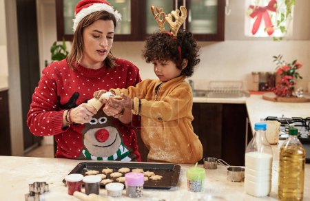 Foto de Mother, son and baking with christmas, snack and dough learning for cookies in kitchen together. Smile, food and celebration with woman, adopted child and boy in home to prepare sweet treat or love. - Imagen libre de derechos