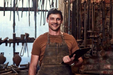 Photo for Happy, metal worker and portrait in workshop with clipboard for manufacturing, welding and blacksmith. Tradesman, smiling and confident in factory with tools for artisan, craftsman and manual labor. - Royalty Free Image