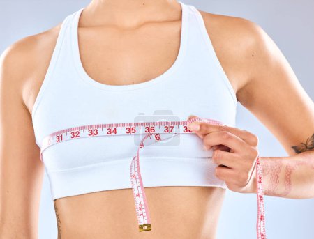 Girl, measure and tape on boobs in studio for chest fitting or underbust measurement, growth and size for fitness or postpartum changes. Woman, isolated and white background with tracking breasts