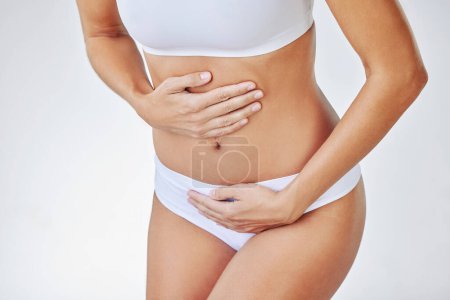 Photo for Girl, pain and hands on stomach in studio for menstruation, ovarian cysts and pelvic congestion syndrome or miscarriage. Woman, underwear and abdominal ache on white background for endometriosis - Royalty Free Image
