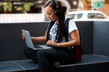 Woman, student and headset with laptop outside, typing and online classes for elearning or education. University, leaner and website research for assignment, listening and podcast or school project.
