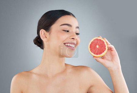 Photo for Smile, woman and fruit for skincare in studio with grapefruit detox, vitamin c and organic product for healthy skin glow. Beauty, cosmetic and nutritionist for facial treatment on grey background. - Royalty Free Image
