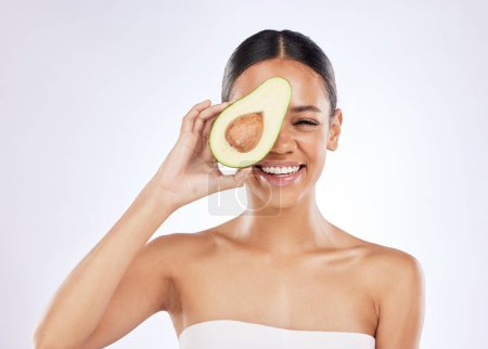 Woman, white background and avocado with natural beauty for skincare with sustainability, fruit oil with cosmetics. Female person, studio and plant based for makeup, portrait with smile for wellness.