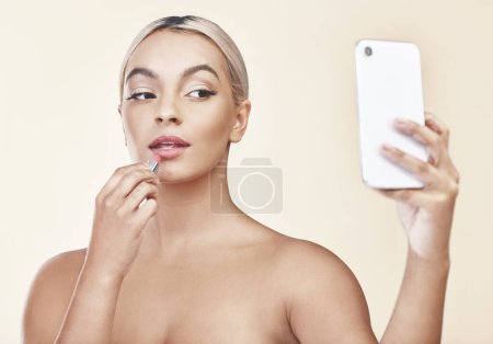 Selfie, femme et rouge à lèvres pour la beauté en studio sur fond de campagne et post médias sociaux. Femme, confiance et influence avec confiance ou satisfait des cosmétiques et du maquillage.