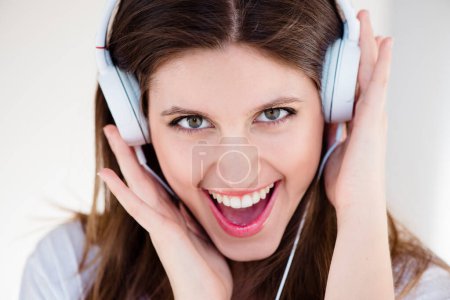 Porträt, Kopfhörer und aufgeregte Frau, die auf weißem Studiohintergrund isoliert Musik, Sound oder Songs hört. Gesicht, singendes und glückliches Mädchen, das Radio-, Audio- oder Kpop-Podcast-Technologie zum Entspannen streamt.