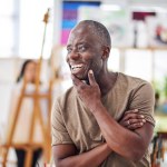 Thinking, happy and African man in art studio for painting, creativity and idea for student workshop. Professor, mature artist and career in education, university and project for college with talent.