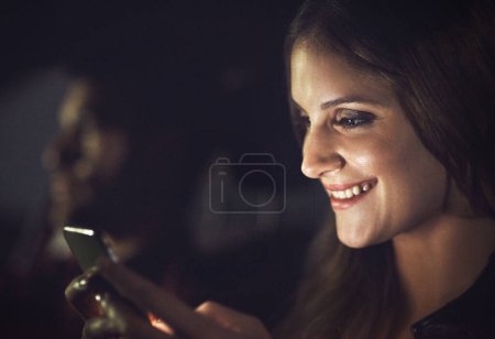 Mujer, pasajero y sonrisa con smartphone por la noche con transporte para viajes, tecnología y comunicación. Conversación, lectura o respuesta a mensajes de texto con chiste en Alemania con taxi
