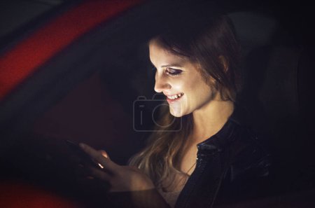 Smile, woman and smartphone in car at night with transport for travel with technology for communication. Reading, social media or replying to text message with joke in New York with personal taxi