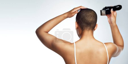 Head, tool and woman shaving hair for cancer treatment, wellness and chemotherapy in studio. Female person, machine and bald for confidence with feminist advocacy and empowerment by white background.