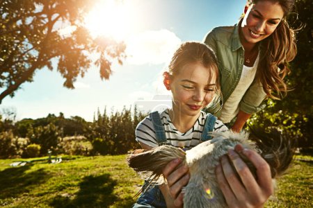 Outdoor, mother and girl with dog, sunshine and care with weekend break, happiness or summer. Park, single parent or mama with daughter, animal or pet with lens flare, fun or child with smile or love.