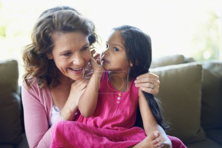 Grandma, girl and whisper on sofa in home with bonding, support and care for child development. People, kid and smile in couch for memories, fun and growth as family together for love and trust.