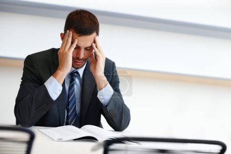 Business man, headache and stress with documents and legal book for deadline on case report in office.Corporate worker, lawyer or attorney reading article with worry, pain or migraine and brain fog.