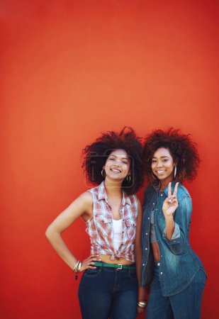 Women, happy and portrait or fashion in studio with casual style, trendy outfit or mockup space on red background. Girls, friends and smile in urban streetwear, afro or peace sign in edgy clothes.
