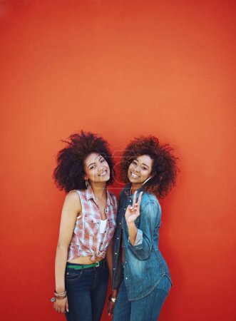 Women, friends and smile or fashion in studio with casual style, trendy outfit or mockup space on red background. Girls, portrait and happy in city with streetwear, afro or peace sign in edgy clothes.