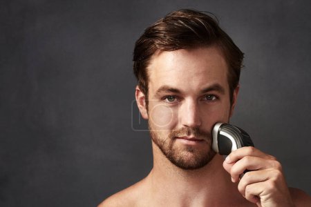Electric, shaving or portrait of man with beard or hair removal tool for skincare or cosmetics in studio. Mockup, space or confident person on grey background for beauty, facial treatment or wellness.