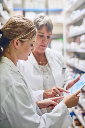 Pharmacist, women and reading together on tablet for charts, stock and analytics with sales stats. People, mentor and intern on digital touchscreen, application and inspection with graphs at store.