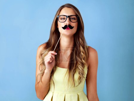 Girl, moustache and happy with prop in studio for pout, photo booth and comic icon with portrait on mockup. Woman, person and funny face with mask on stick for celebration and fun on blue background.