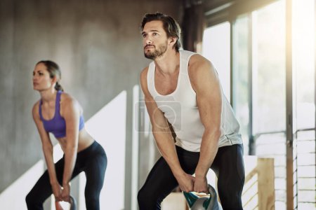 Exercise, fitness and couple in gym with kettlebell, power and workout challenge together at sports club. Man, woman and personal trainer with weights, muscle development and healthy body training
