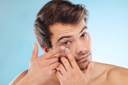 Grooming, man and squeezing pimple in morning, routine and wellness in skincare, hygiene and blue background. Male person, cosmetic and popping for blemish, confidence and clean in studio backdrop.