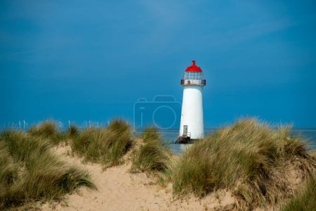 The sand dunes, and the grade II listed building Point of Ayr Lighthouse at Talacre beach in North Wales, UK on a sunny summer day.