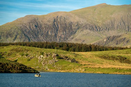 Anglers fishing from a boat on Llyn Dywarchen in the Eryri National Park, Wales with Yr Wyddfa in the distance.