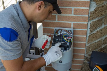 Electrician technician carrying out the repair and programming of a technical data sheet of the motor of an automatic driveway gate. 