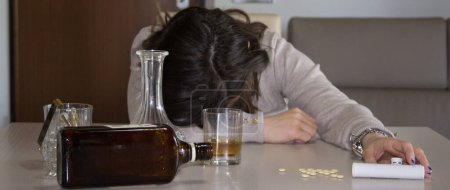 Photo for Image of a young woman passed out on the table after abusing alcohol and psychotropic drugs. Reference to the abuse and dependence of these substances. Horizontal banner - Royalty Free Image