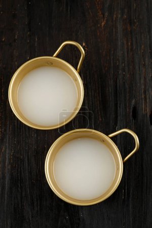 Téléchargez les photos : Makgeolli vue du dessus en deux tasses traditionnelles coréennes, vin de riz coréen sur table en bois - en image libre de droit