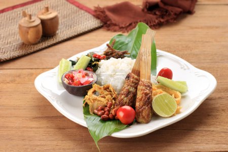 Photo for Nasi Campur Bali, Indonesian Balinese Mix Rice with Sate Lilit, Ayam Sisit, Sambal Matah, and Peanut - Royalty Free Image