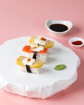 Foto de Enfoque seleccionado Tamago y Cangrejo Sushi Roll en la placa de piedra blanca, fondo rosa - Imagen libre de derechos